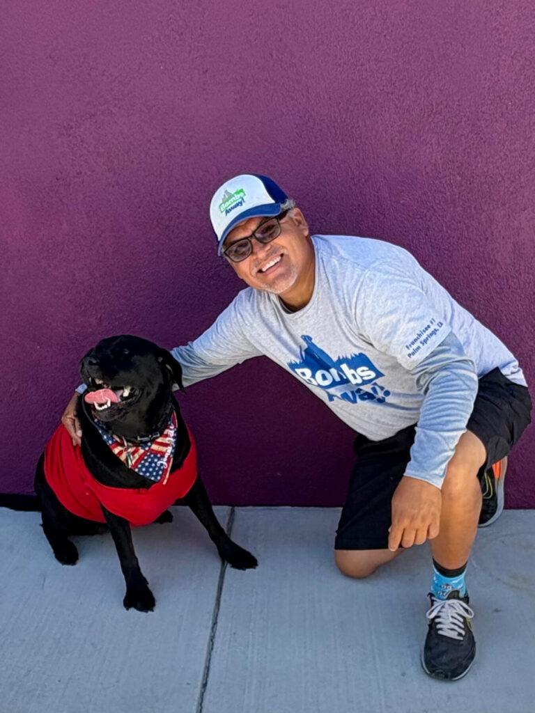 Bombs Away team member hugging a dog and smilling