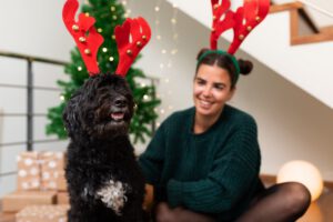 Woman and dog celebrating Christmas together, both wearing reindeer horn ornaments